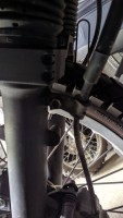 In Fahrtrichtung links unterhalb des Faltenbalgs.